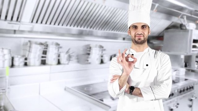 Male Caucasian chef showing OK sign while wearing uniform and standing in the kitchen