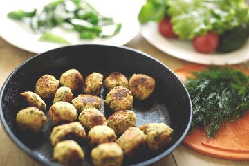 Fried falafel in a cast-iron pan close up. Middle eastern dish falafel pan and dishes with salad on the wooden background