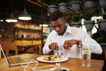 Aafrican man have dinner at cafe after work with laptop.