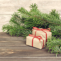 Fototapeta na wymiar Toned Christmas background with Christmas gift on wooden background with Fir branches. Xmas and Happy New Year composition. Flat lay, top view