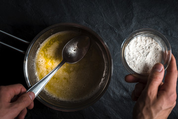Flour is poured into a saucepan with melted butter close-up