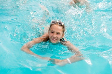 Fototapeta na wymiar Beautiful girl in a swimsuit swims in the pool