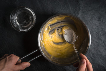 Adding flour to the melted butter on a gray table