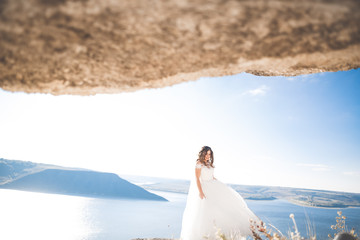 Fototapeta na wymiar Pretty lady, bride posing in a wedding dress near sea on sunset
