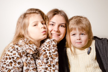 Happy cheerful attractive family kids wearing coats ready for winter season lifestyle. Close up portrait of joyful hugging people with healthy smile on light background