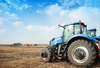 Obraz premium Two blue tractors in the empty field.