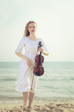 Woman on beach near sea holding violin