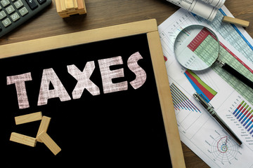 Text Taxes on the blackboard on the desk with office business accessories