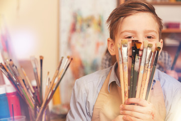 Funny teenage boy playing with brushes while posing for camera