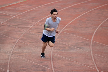 Lifestyle of young healthy Asian runner man running on racetrack in stadium