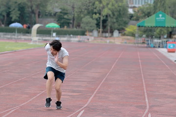 Obraz premium Handsome athlete Asian man running on racetrack in stadium with copy space background. Healthy active lifestyle concept.