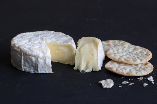 Camembert soft creamy cheese and crackers on black background - Space for text