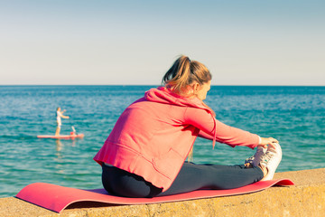 Woman doing sports exercises outdoors by seaside