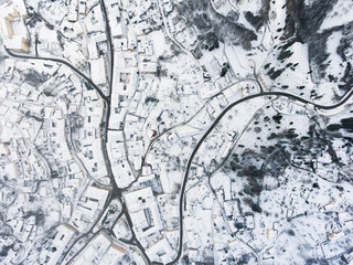 Aerial view of small town with hills in winter.