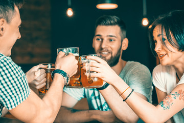 Friends toasting with glasses of light beer at the pub. Beautiful background of the Oktoberfest. A group of young people while relaxing at the bar. fine grain. Soft focus. Shallow DOF