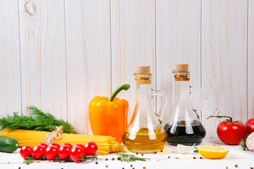 Spaghetti, tomatoes cherry, olive oil, herb and spices on old white wooden background. Set for healthy foods. Ingredients for salad.