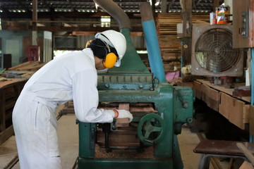 Fototapeta premium Professional young worker in white safety uniform working with planing machine in factory.