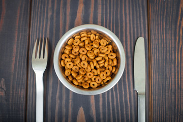Cat food and cutlery on a wooden table.