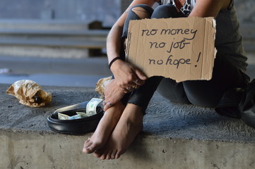 a homeless punk woman begging, holding a sign - no money no job no hope 