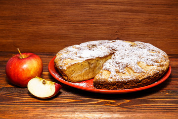 Apples and freshly baked apple pie on a rustic background of dark wood.