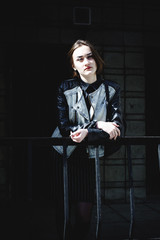 street portrait of a girl student, fashionably dressed in dark clothes, with a black backpack and denim jacket autumn sunny day