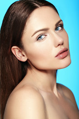 Glamor closeup beauty portrait of beautiful sensual Caucasian young woman model with nude makeup with perfect clean skin isolated on blue background