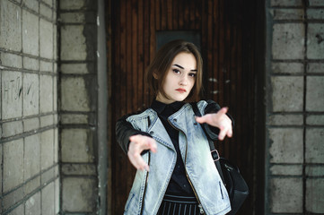 street portrait of a girl student, fashionably dressed in dark clothes, with a black backpack and denim jacket autumn sunny day
