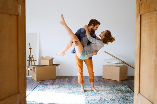 Man carrying woman in his arms, moving in new house.