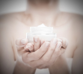 Woman's hands holding a face creme jar.