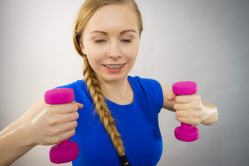 Teenage woman working out at home with dumbbell