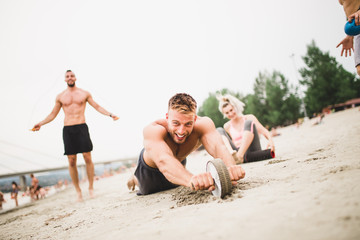 Fototapeta premium Group young attractive people having fun on beach and doing some fitness workout.
