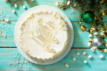 Fototapeta na wymiar Birthday cake with white chocolate icing on a festive Christmas table. Top view.