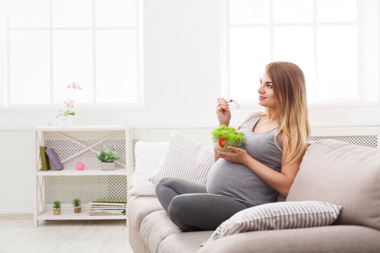Young pregnant woman eating fresh green salad
