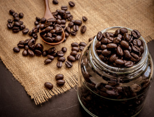 Coffee bean grain in a glass bottle on black table with sack fabric