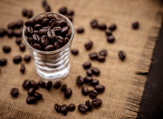 Coffee bean grain in a glass bottle on black table with sack fabric