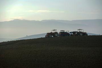 Fototapeta premium Farmer in tractor preparing land with seedbed cultivator