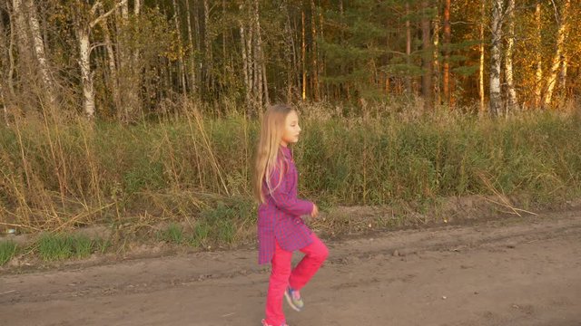 Happy young girl dancing outdoors. Cheerleader training at farm road sunny evening. Handheld.