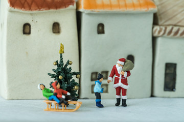 miniature figure Santa claus giving present to happy children as christmas celebration concept
