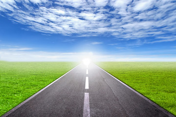 asphalt road through the green field and clouds on blue sky in summer day