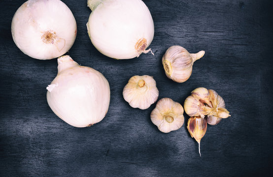 fresh white onion and garlic fruits on a black background, top view