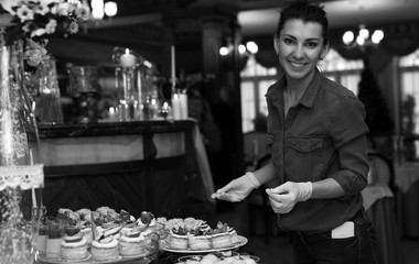 table with sweets and a variety of sweet snacks against the backdrop of  a girl confectioner