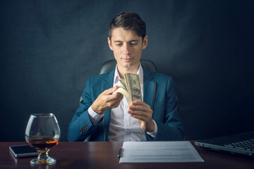 Man Businessman in suit holding money in his hands. Salary the form of dollar bills. Concept of a successful business