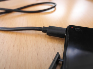 Charging a black smartphone with usb charging cable