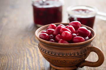Ripe cornel berries in ceramic mug and dogwood jam