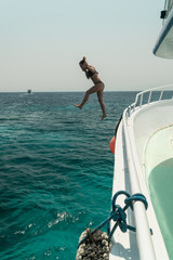 Naklejka premium Girl jump into the water from the yacht