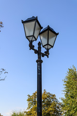 Fototapeta na wymiar Vintage iron lighting pole with twin double lamp lantern on background of dark blue sky