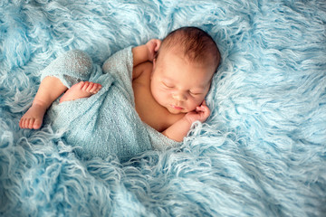 Happy smiling newborn baby in wrap, sleeping happily in cozy fur © Tomsickova