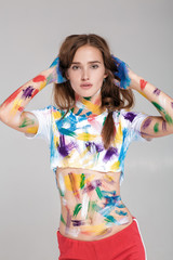 young woman smeared in multicolored paint.
