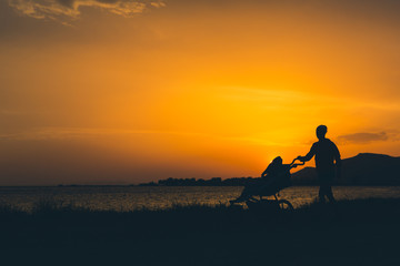 Mother walking on a beach with stroller enjoying motherhood
