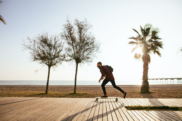 Man riding on longboard on beach promenade.